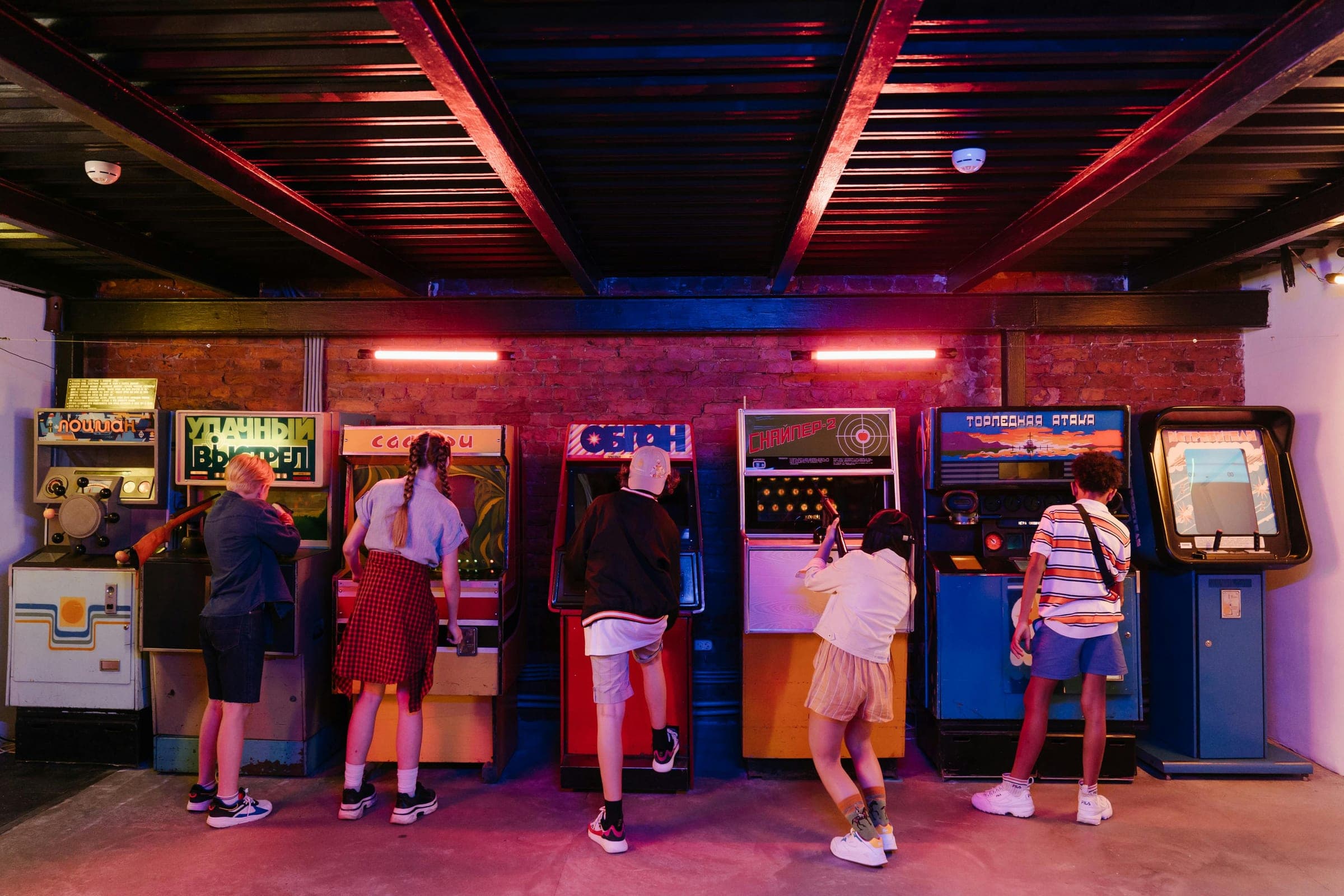 Players at a row of glowing arcade machines