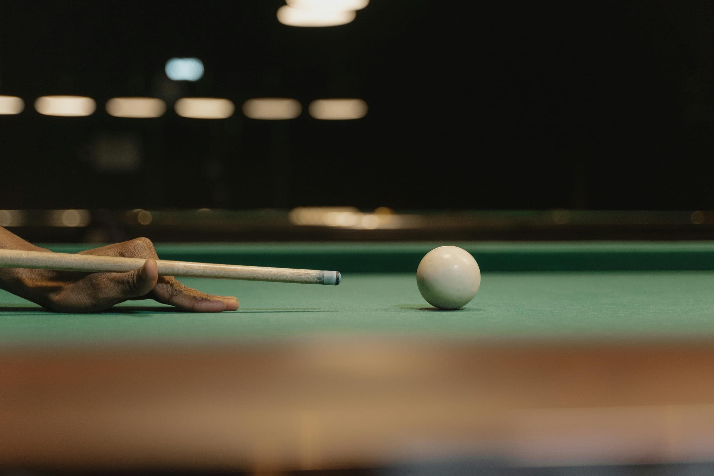 A cue lined up with the white ball on a billiards table
