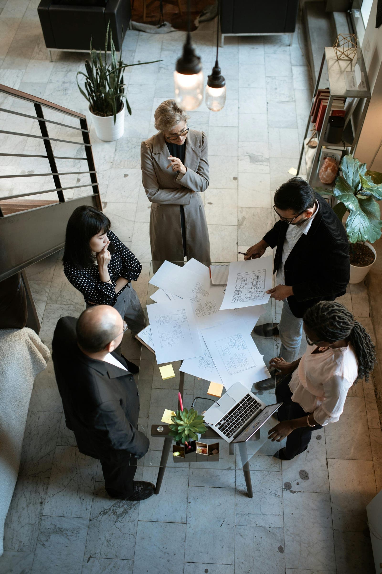 A team gathered around a table of plans, from above