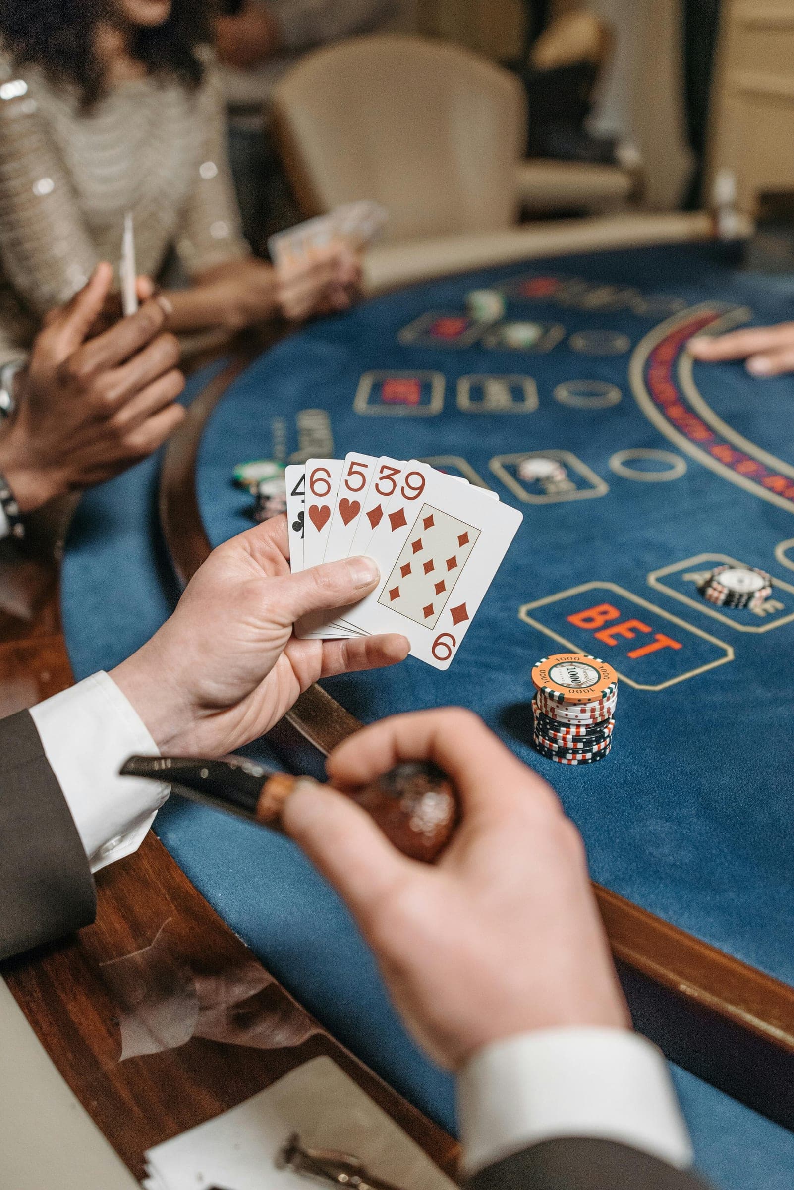Hands holding playing cards over a poker table