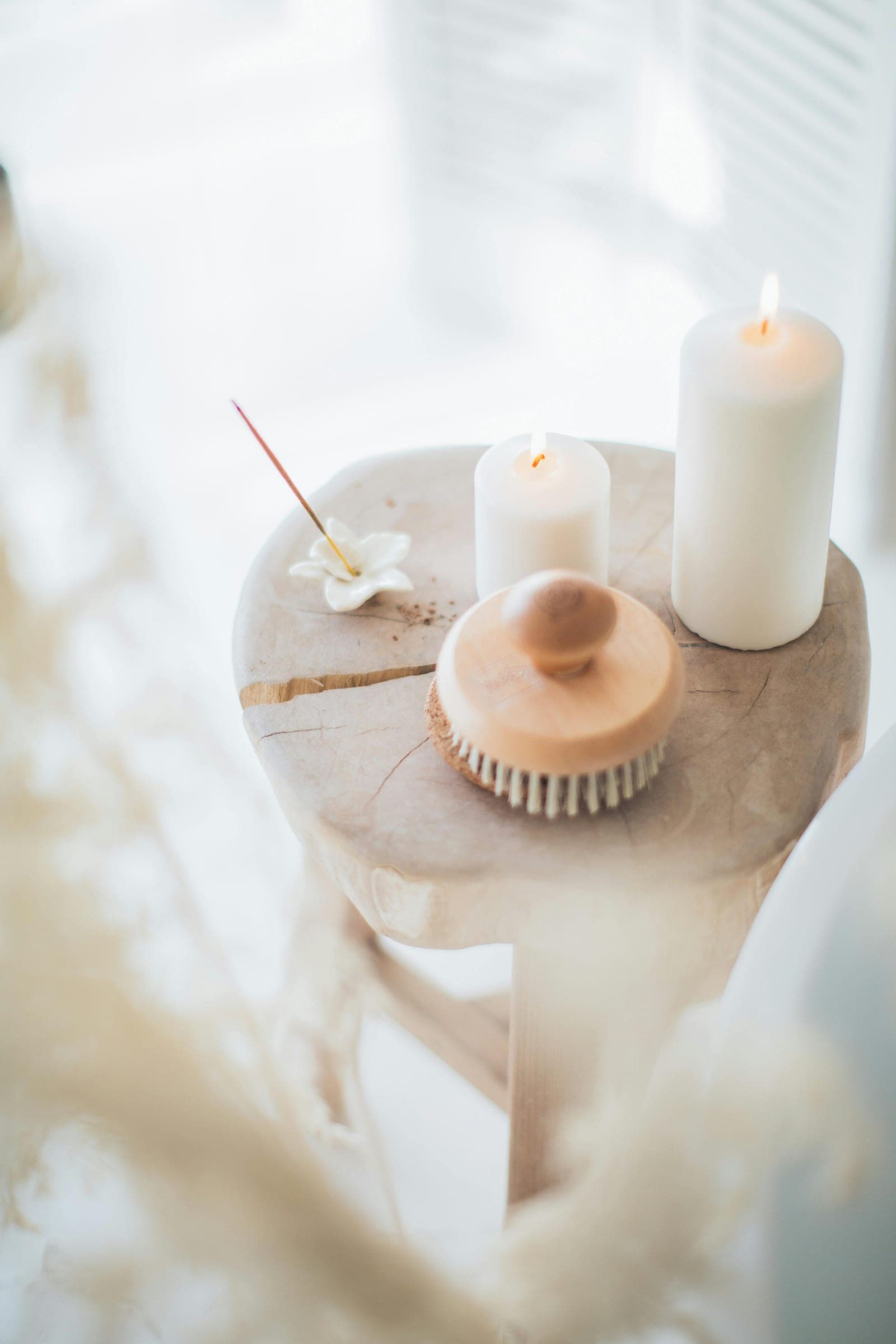Candles, a bath brush and a frangipani on a stone spa table