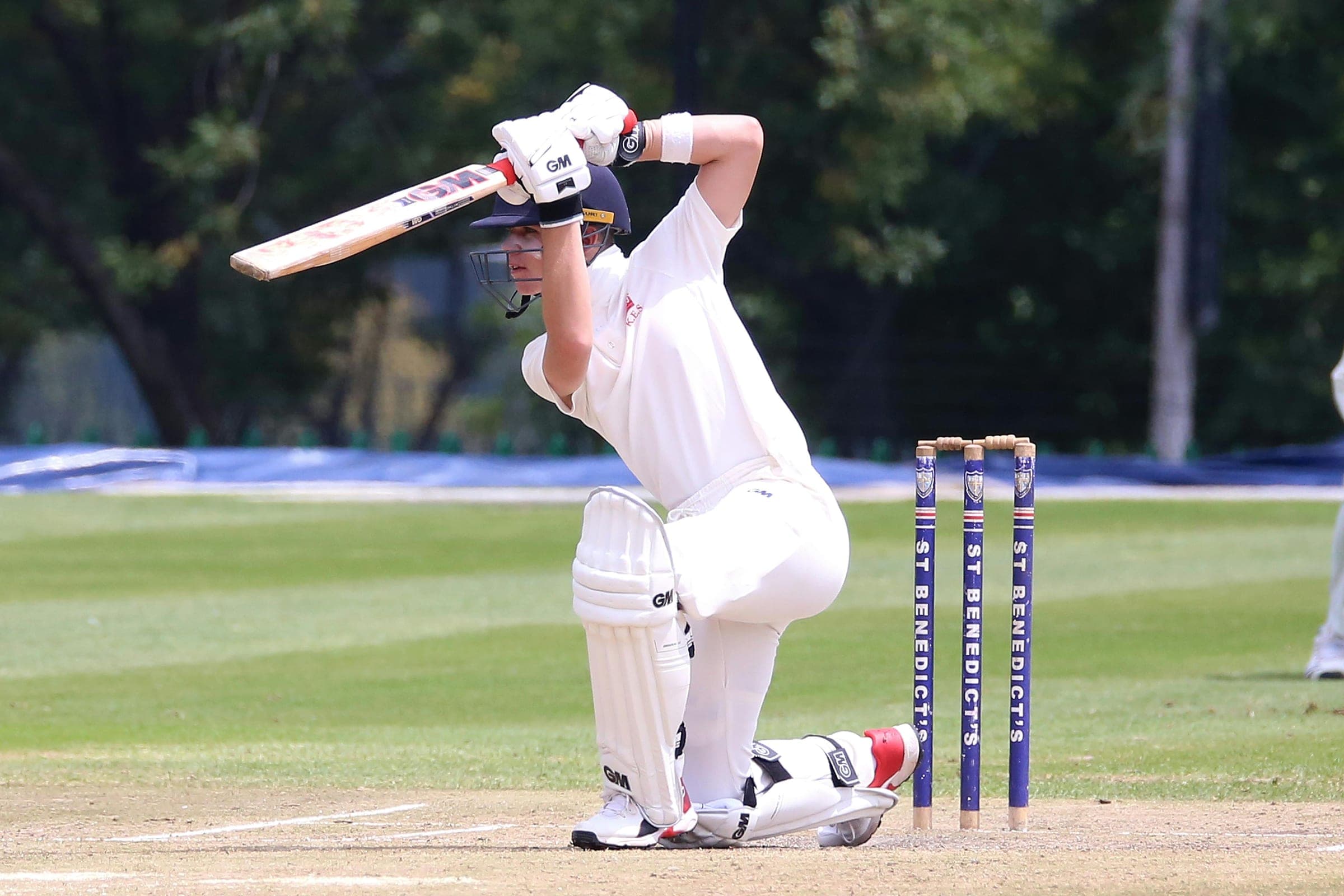 A batter in whites playing a defensive stroke at the crease