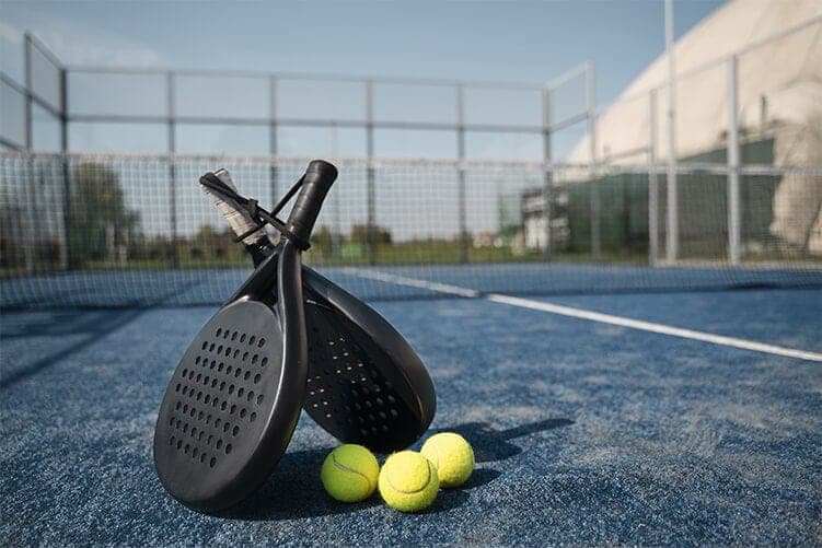 Two padel rackets and balls on a blue court